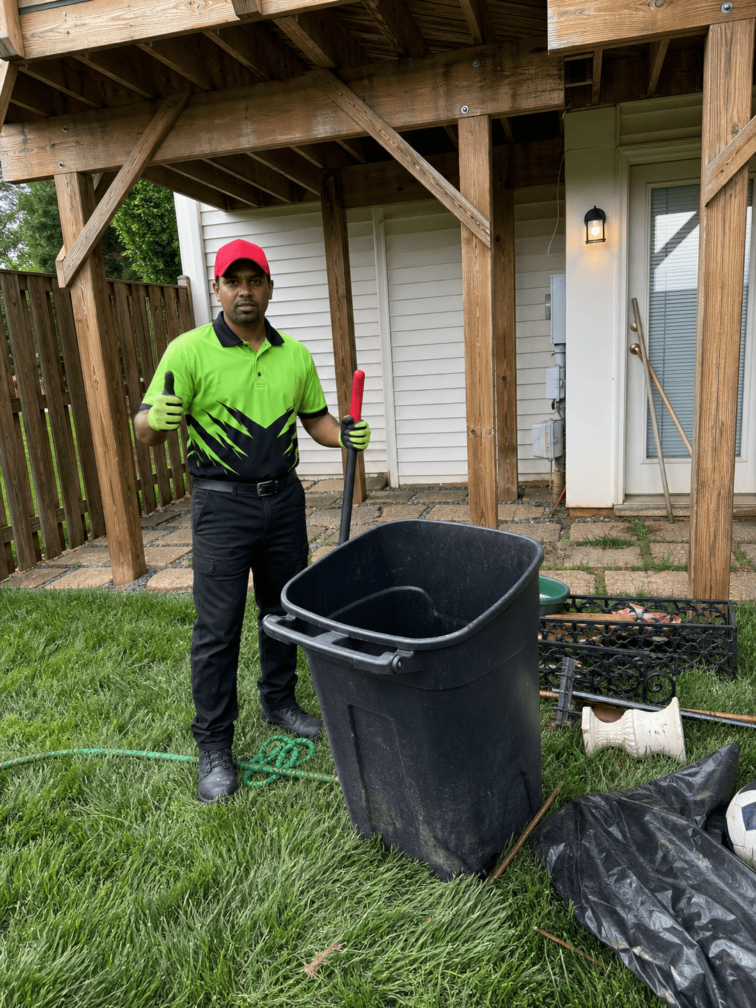 Wee Haul crew member clearing a backyard patio of old bins, planters, and yard junk
